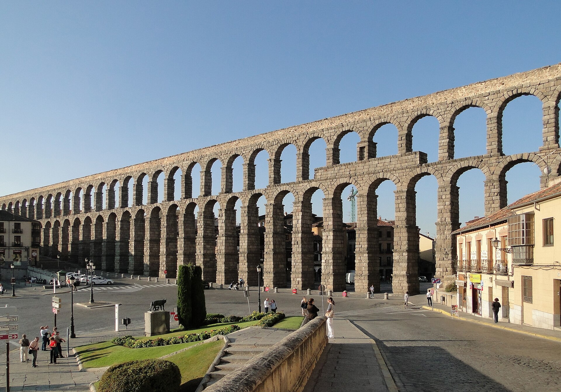 Acueducto de Segovia en la plaza del Azoguejo, con estatua de toro y un palacio de fondo.